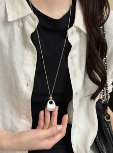 Detail van een Franse vintage matte zilveren hanger ketting op linnen shirt achtergrond