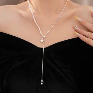 Detailansicht einer eleganten asymmetrischen Stern- und Perlenkette am Schlüsselbein eines Models.