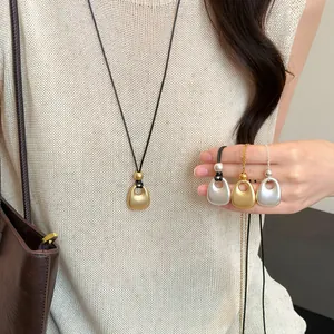 Detailopname van goud- en zilverkleurige retro metalen hangers op een gebreide top.