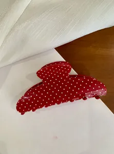 Detailed view of a trendy large red hair claw clip featuring stylish white polka dots