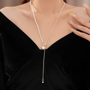 Elegante asymmetrische Perlenkette und Silberkette getragen als langer Tropfenanhänger