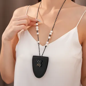 Detailansicht einer schwarzen Brillenhalter-Halskette aus Leder mit weißen Perlen und Bär