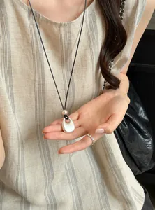 Detailweergave van de zilveren ronde hanger ketting met parel op een zwart koord