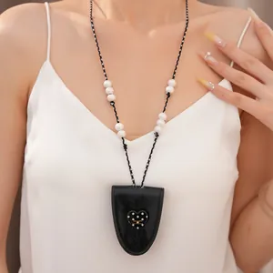 Detailansicht einer schicken Leder-Herzanhänger-Halskette mit eleganten Perlen an einem Model