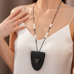 Elegante Nahaufnahme einer Leder-Herzkette mit Punkten und Perlen an einem weiblichen Modell