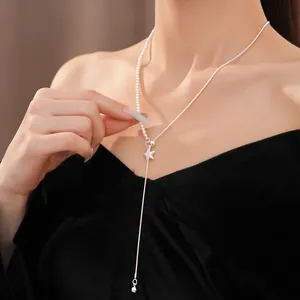 Detailaufnahme einer asymmetrischen Stern- und Perlenkette an einem weiblichen Model.