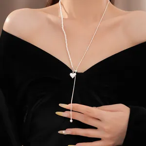 Detailansicht einer asymmetrischen Herz-Halskette mit Perlen auf einem schwarzen Samt-Outfit