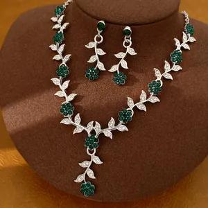 Close-up of vintage jewelry set with emerald green crystals and silver leafy vines