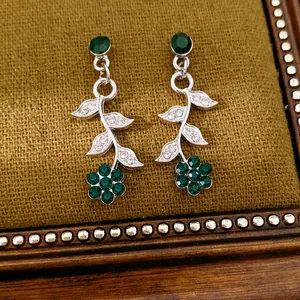 Detailed close-up view of vintage silver earrings featuring green flower and rhinestone leaves
