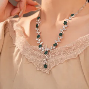 Detail view of a vintage silver necklace with green floral motifs and rhinestone leaves