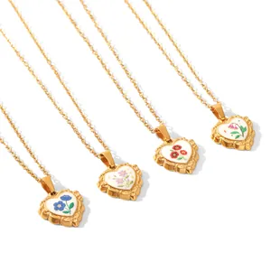 Vue détaillée de quatre colliers cœur en acier doré avec fleurs en émail.