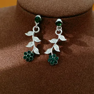 Detail view of vintage-style green crystal flower and leaf drop earrings