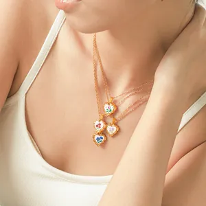 Vue détaillée de colliers cœur en acier doré 18 carats avec jolies fleurs en émail.