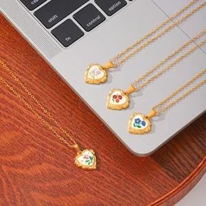 Vue détaillée de quatre pendentifs en émail en forme de cœur avec motifs floraux dorés