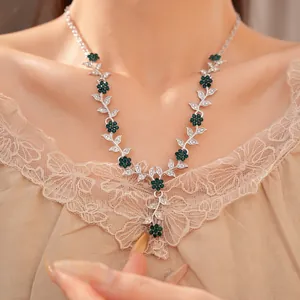 Detail view of a vintage vine necklace with green rhinestones and silver finish on a model