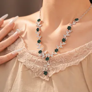 Close-up of vintage floral necklace with emerald green crystals and silver leaf detail.
