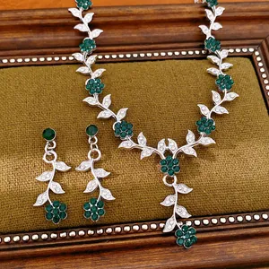Detailed macro view of vintage jewelry set featuring silver leaf and green flower crystals