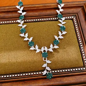 Detailed view of a vintage floral necklace with emerald green and clear rhinestones.