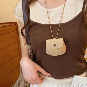 Gedetailleerde close-up van een vintage beige leren tasjesketting gedragen door een model