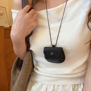 Detailopname van een vintage zwarte leren tas ketting gedragen door een vrouwelijk model