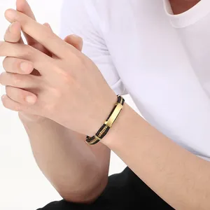 Gros plan d'un bracelet pour homme en cuir tressé et acier avec une plaque dorée courbée.