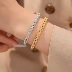Gedetailleerde weergave van goud en zilver vergulde zirkoon schakelarmbanden om pols