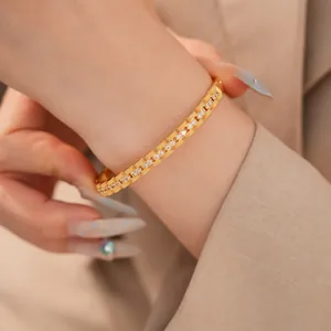 Detailopname van een luxe 18K vergulde zirkonia vierkante schakelarmband om pols