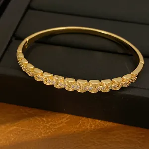 Close-up van een 18K vergulde armband met details van vierkante zirkonia-blokken