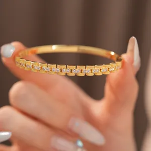 Close-up van een 18K vergulde armband met vierkante schakels en fonkelende zirkoniasteentjes