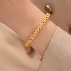 Detailopname van een 18k vergulde zirkoon armband met vierkante gesp om een vrouwelijke pols.