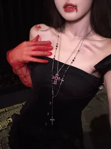 Detail of a double-layered gothic necklace with red glass beads and multiple cross pendants