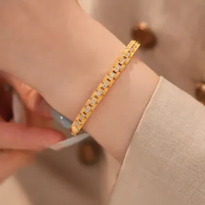 Detailopname van de zirkonia-details en de vierkante sluiting van een gouden armband