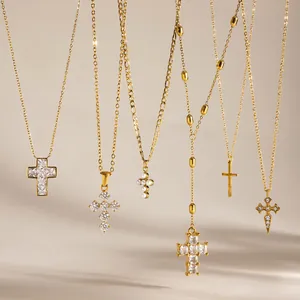 Dettaglio di eleganti collane a croce placcate in oro con zirconi e perle