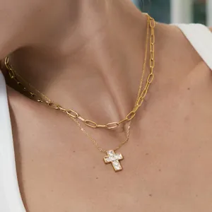 Dettaglio ravvicinato di una collana a doppia catena con croce d'oro e zirconi