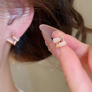 Close-up detail of geometric cat eye stone earrings with rose gold finish