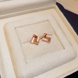 Close-up of geometric cat-eye stone earrings in a plush beige jewelry gift box.