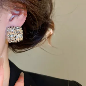 Detailansicht von silbernen geflochtenen Knotenohrsteckern mit Vintage-Metalltextur
