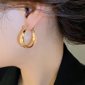 Detailansicht eleganter goldener Doppelcreolen im Vintage-Stil am Ohr eines Models