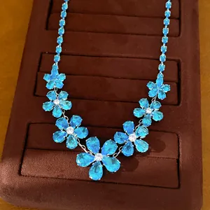 Close-up detail of blue zircon flower necklace on brown velvet display tray