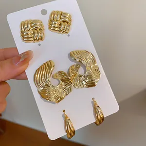 Detailaufnahme von drei Paaren goldfarbener Metallohrringe mit Faltenstruktur.