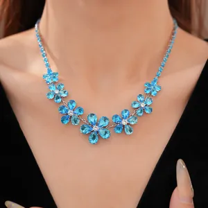 Close-up view of elegant blue zircon flower necklace worn by a model in black dress