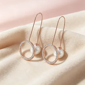 Nahaufnahme eleganter langer Hakenohrringe mit glitzernden Kristallen und Perlen.