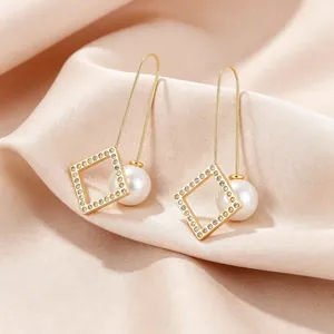 Detailaufnahme eleganter goldener geometrischer Ohrringe mit Kristallen und weißen Perlen