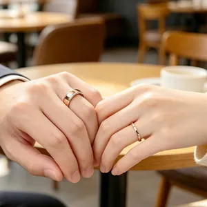 Gros plan de bagues minimalistes en acier titane or rose sur les mains d'un couple.