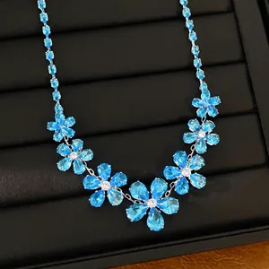 Detailed macro view of an elegant light blue zircon flower necklace on a black tray