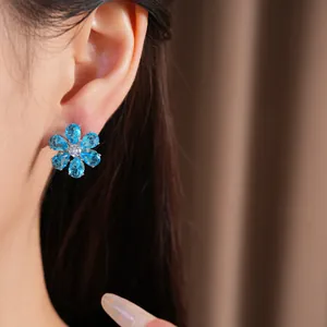 Elegant blue zircon flower stud earring featured in a close-up shot on a model ear