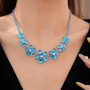 Detailed view of an elegant blue zircon flower necklace worn by a model in a black dress