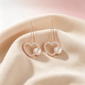 Detailaufnahme eleganter herzförmiger Ohrringe mit Muschelperle und Pavé-Strasssteinen