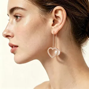 Elegante roségoldene Herz-Ohrringe mit Strasssteinen und weißer Perle am Ohr des Models