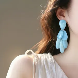 Elegant close-up of blue marbled teardrop tassel earrings worn by a fashion model